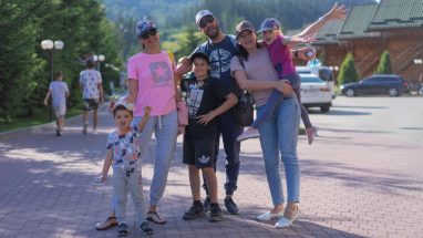 A joyful family of six spending quality time together in a scenic outdoor setting with mountains in the background.